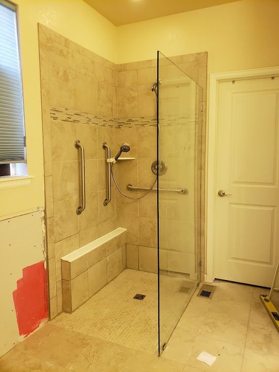 A bathroom with a walk in shower with a glass door.