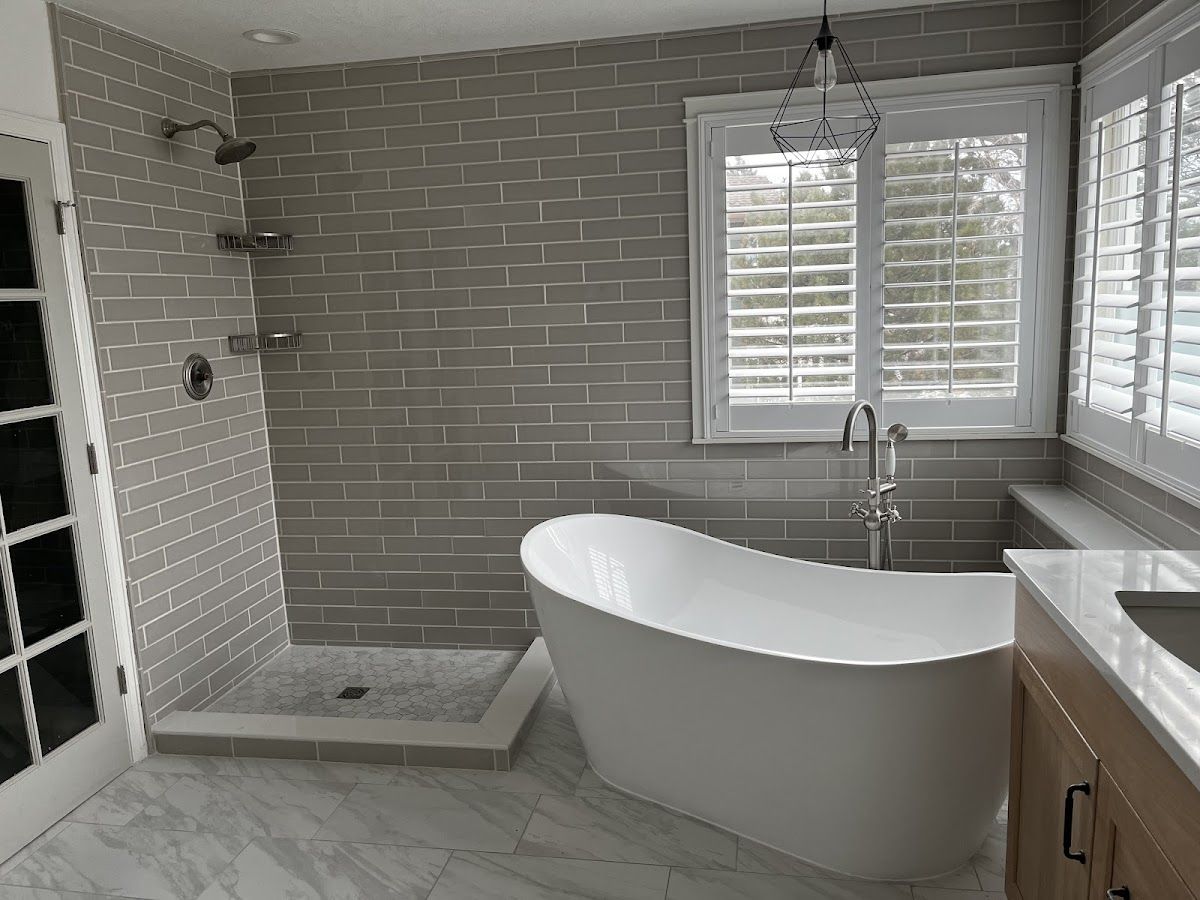 A bathroom with a tub , shower , sink and window.
