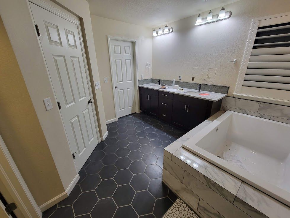 A bathroom with two sinks , a tub , and a walk in closet.