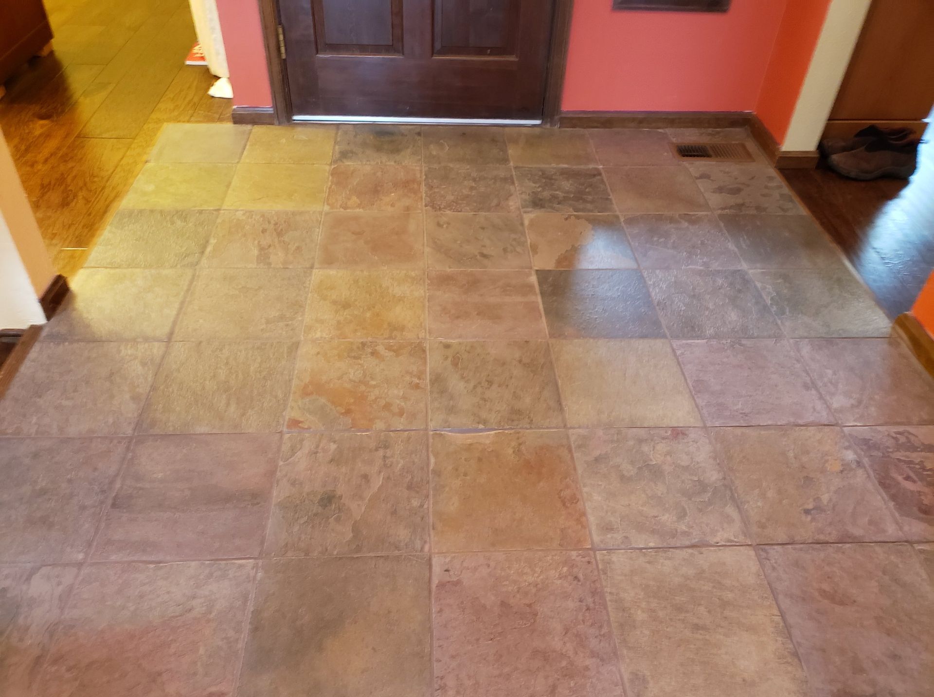 A tiled floor in a hallway next to a door.