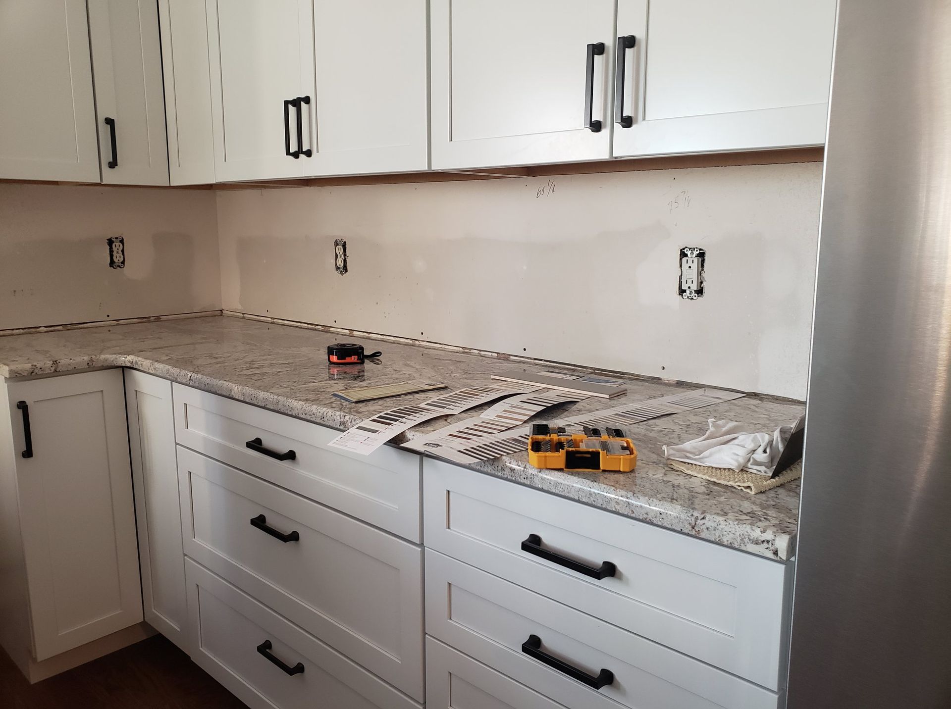 A kitchen with white cabinets and granite counter tops is being remodeled.