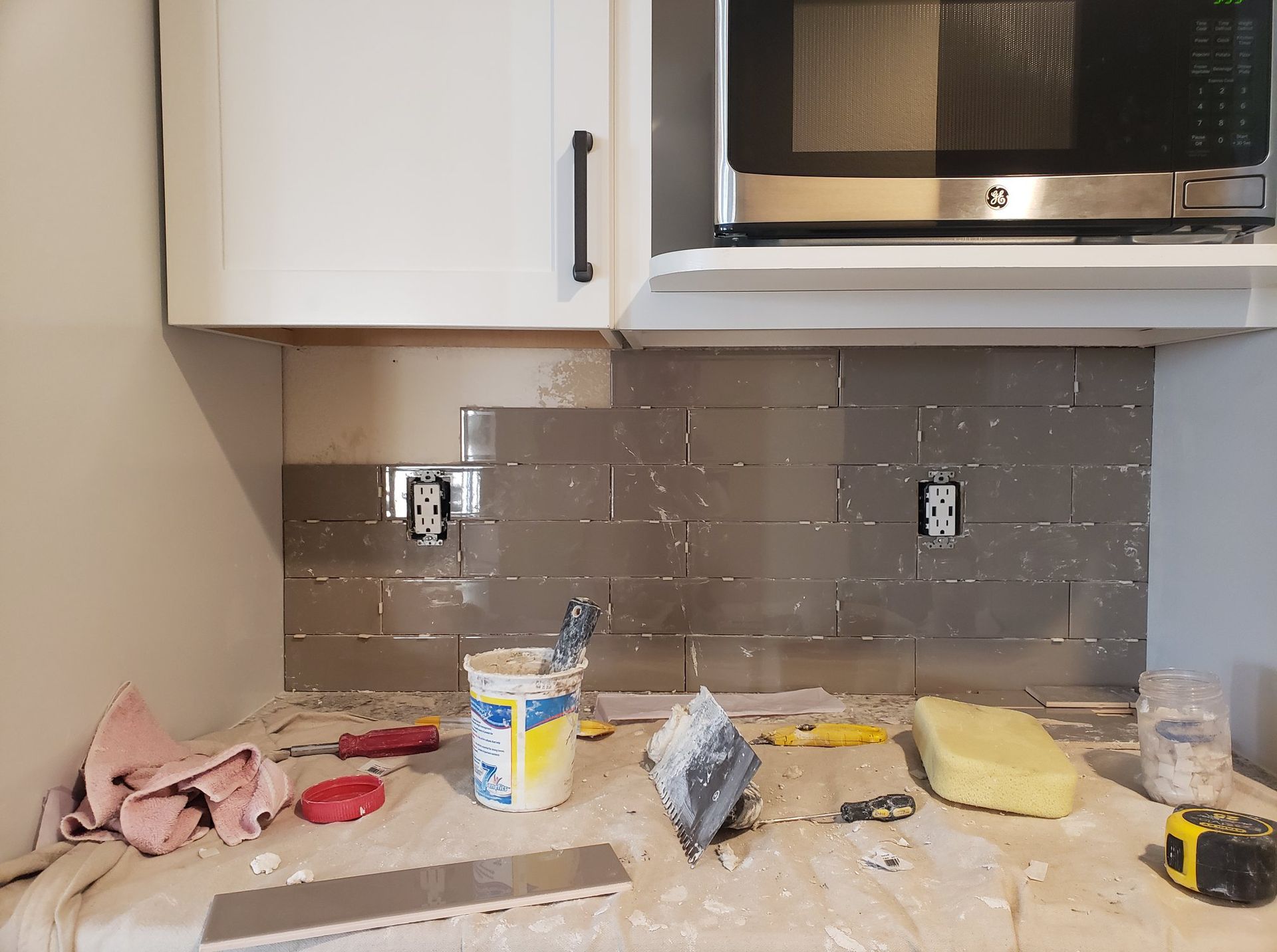 A kitchen with a microwave and a sponge on the counter