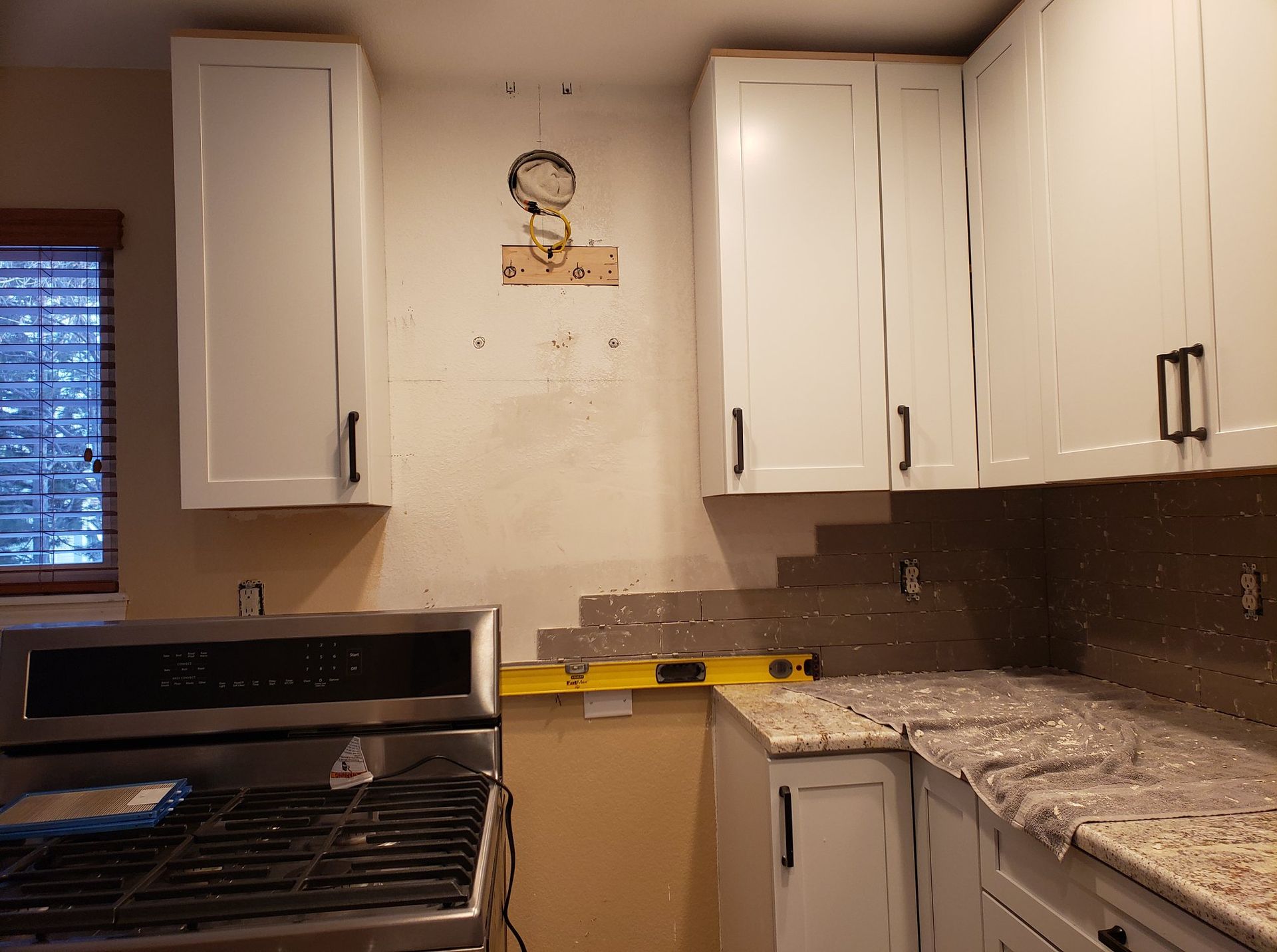 A kitchen with white cabinets and granite counter tops is being remodeled.