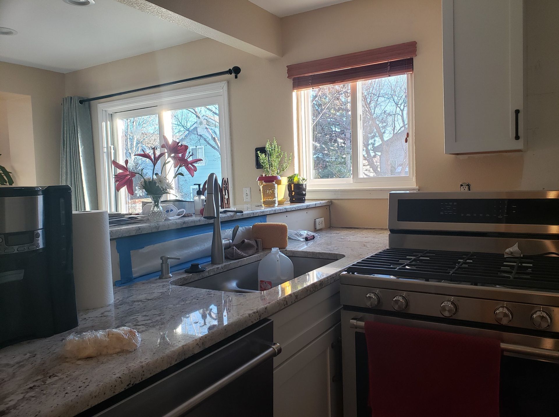 A kitchen with a stove , sink , and window.