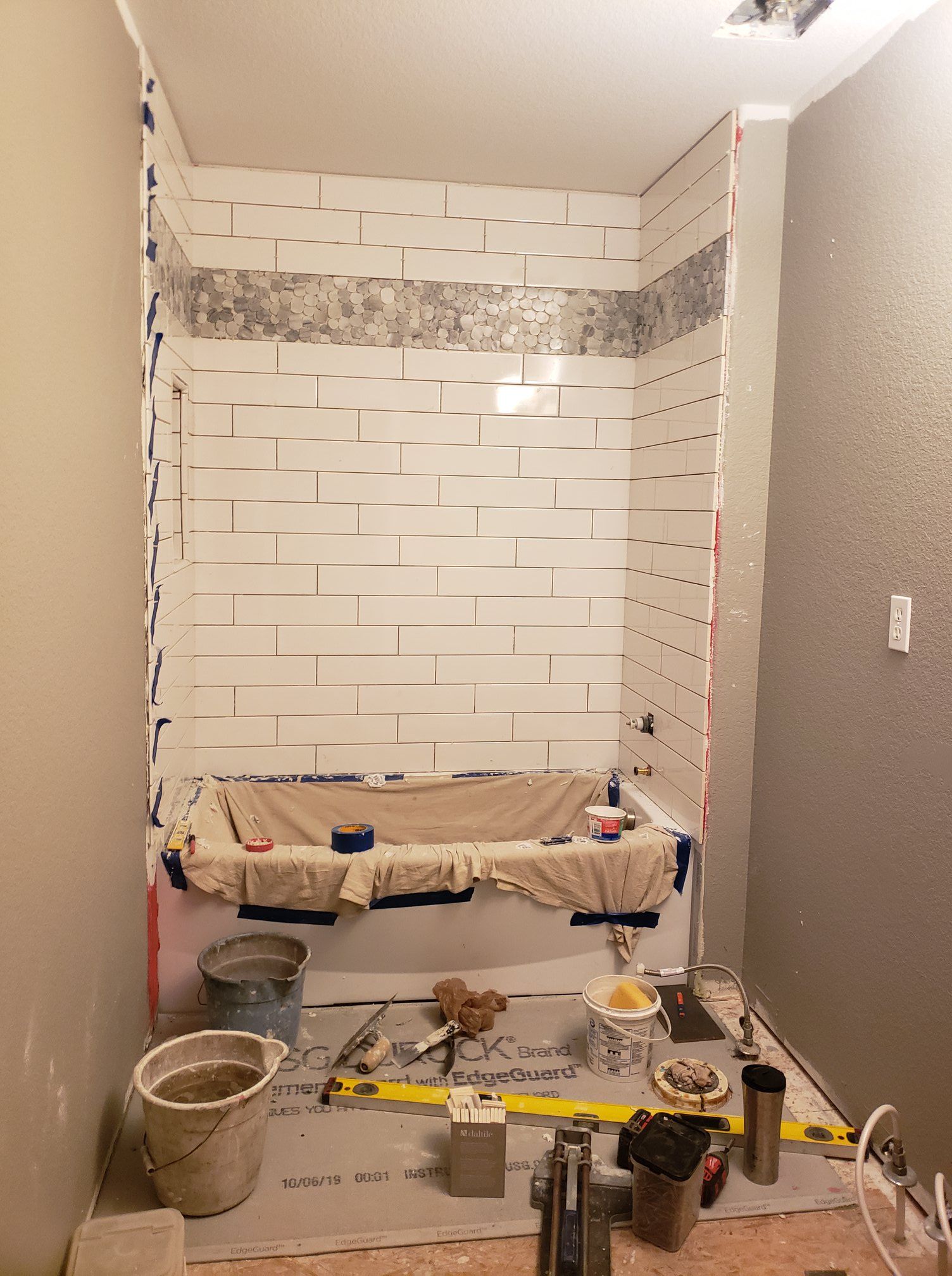 A bathroom is being remodeled with a bathtub and a brick wall.