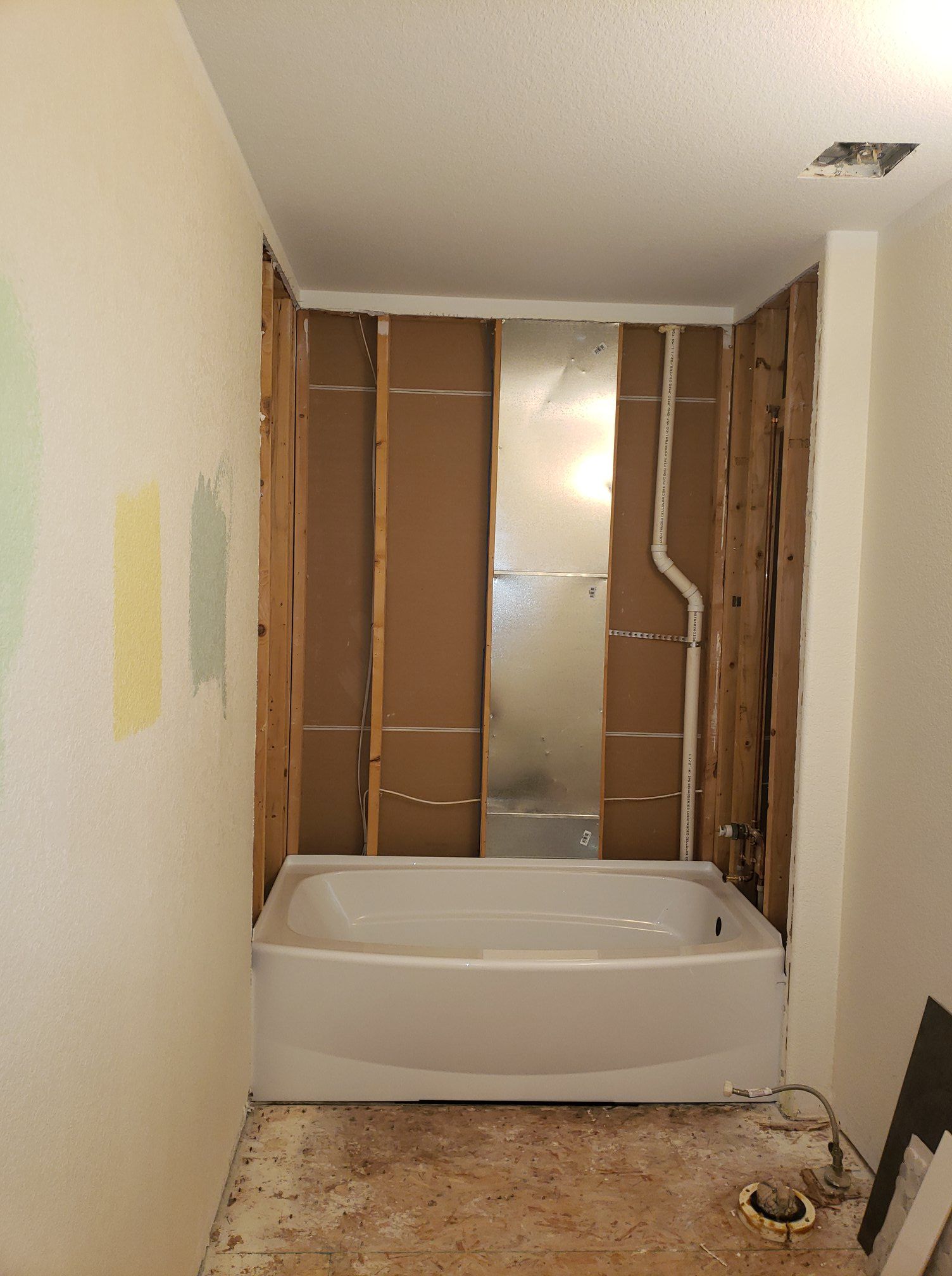 A bathtub is sitting in a bathroom under construction.