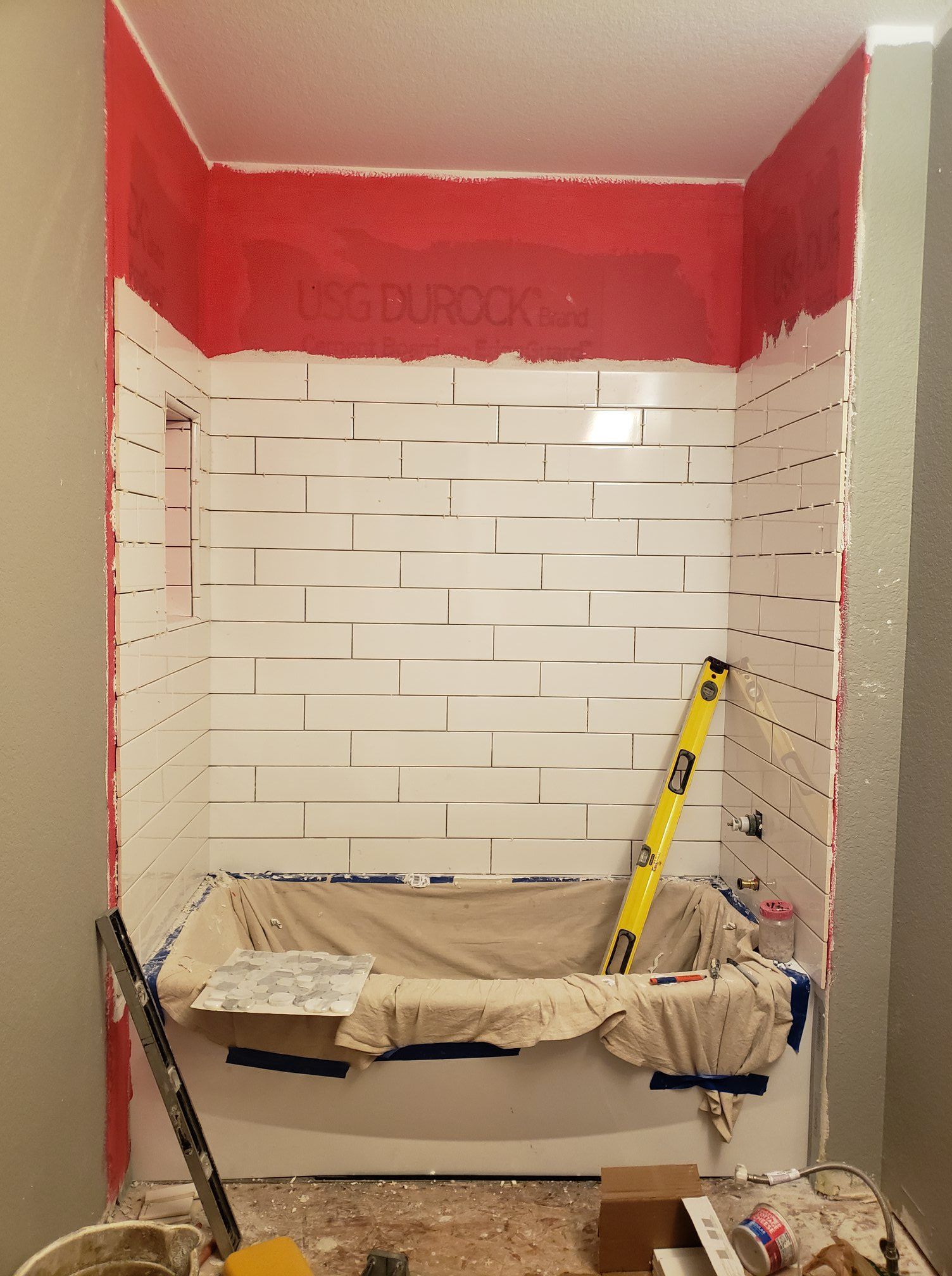 A bathroom with white tiles and a yellow level on the floor