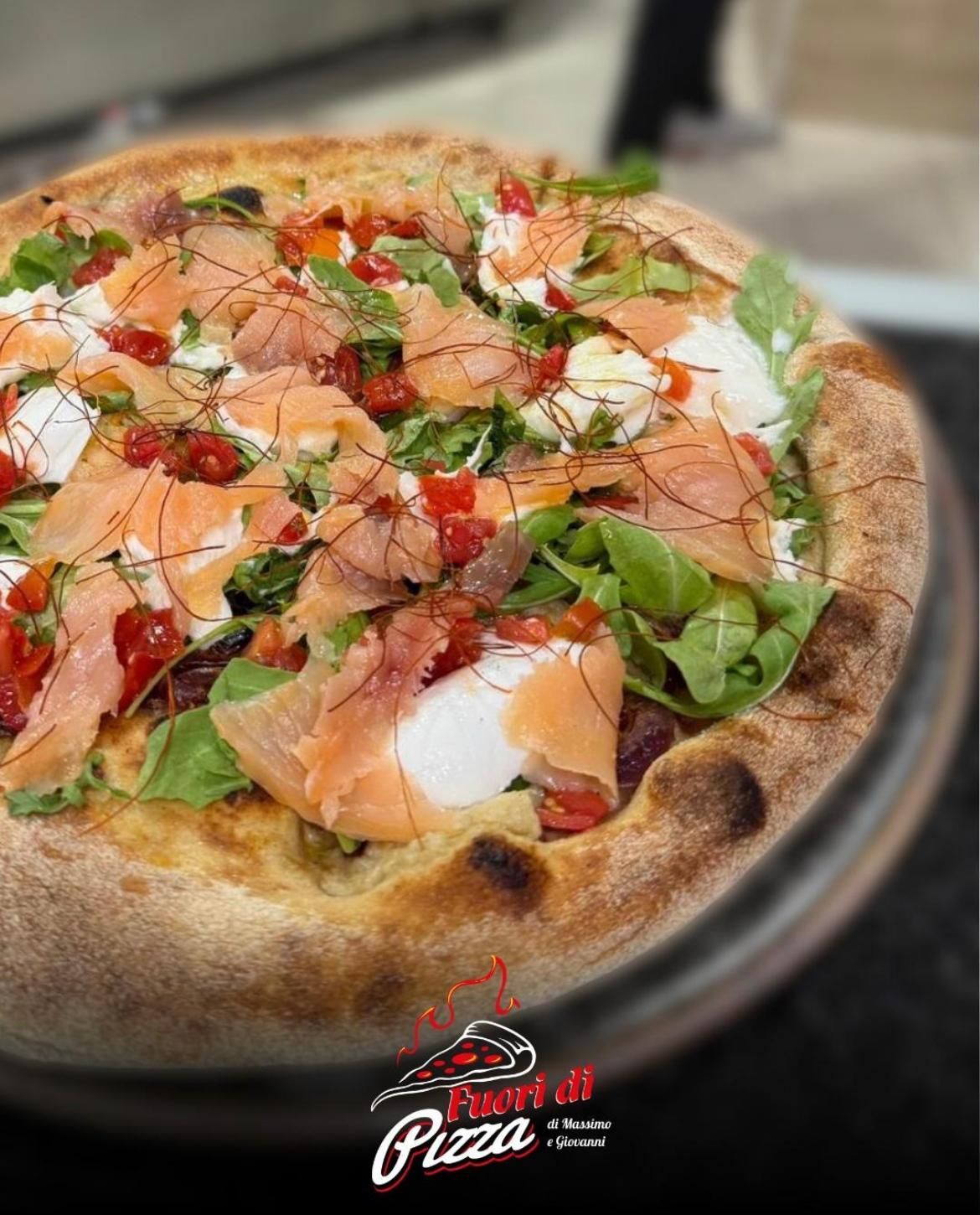 Uno chef utilizza una lunga pala per cuocere le pizze in un forno di pietra incandescente rivestito di mattoni all'interno di un ristorante.