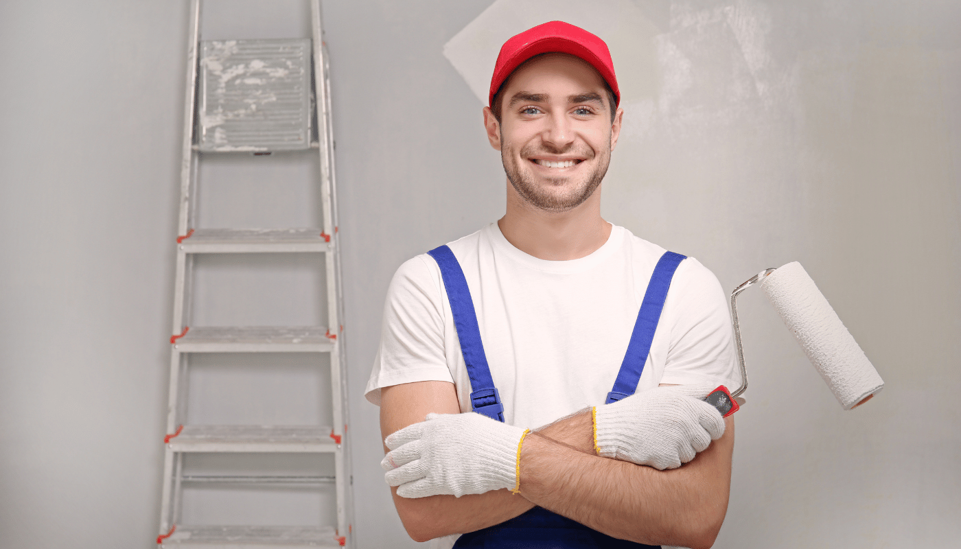 A man is holding a paint roller in front of a ladder.