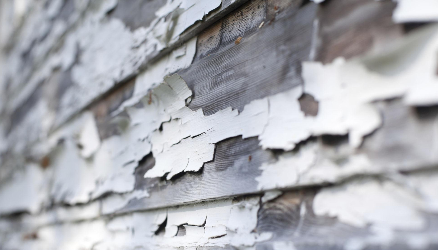 Close-up of weathered wooden siding with peeling white paint.