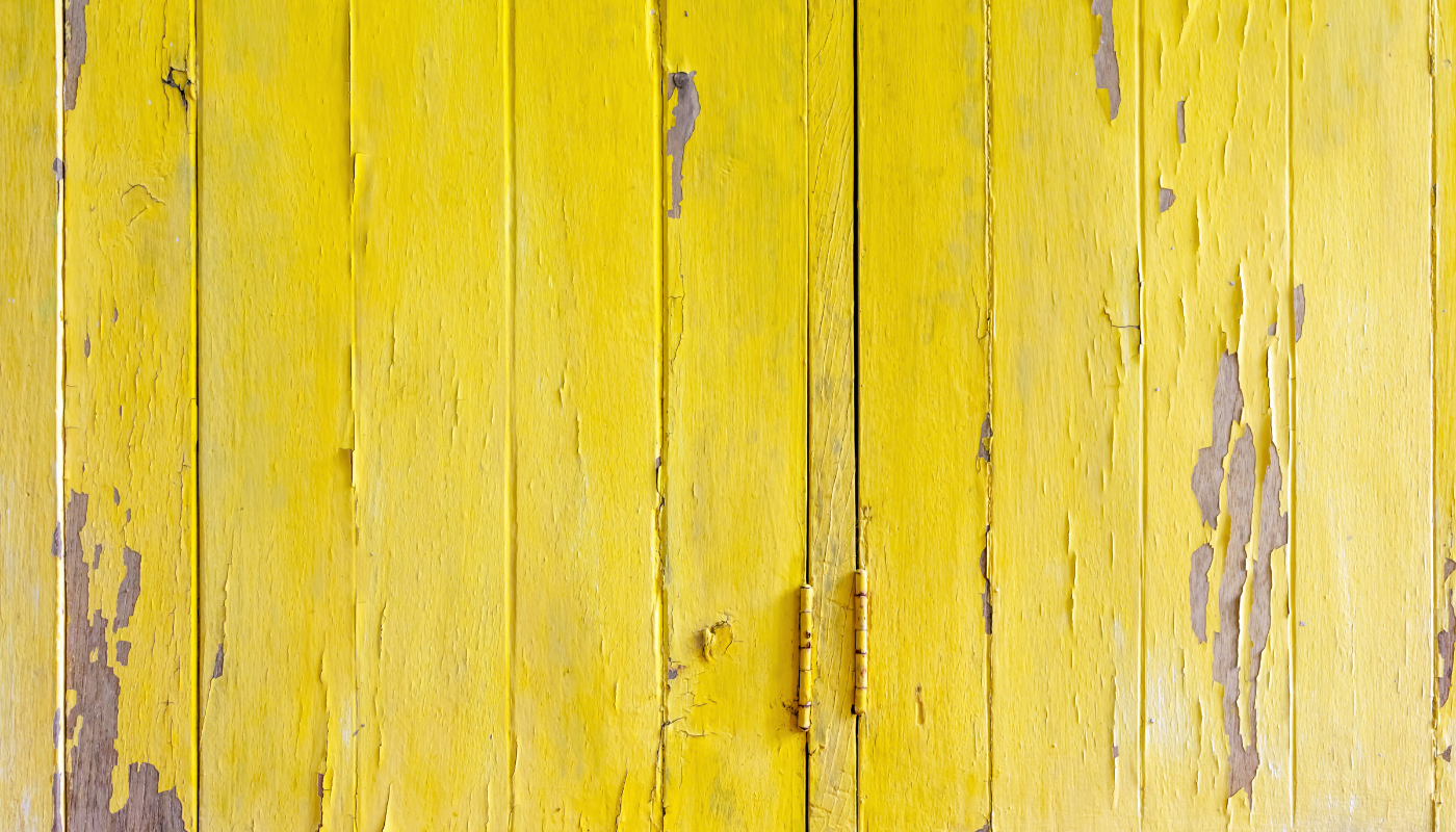 Yellow, weathered wooden planks; paint peeling to reveal wood grain.
