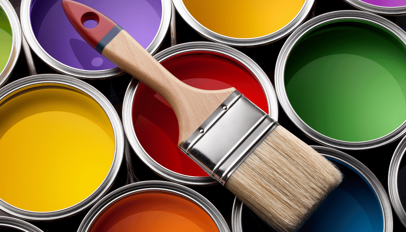 A brush is sitting on top of a pile of paint cans.