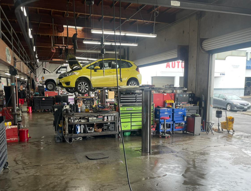 Auto repair shop interior with a yellow car lifted on a hoist and tools scattered around. | Lee Rollins Firestone