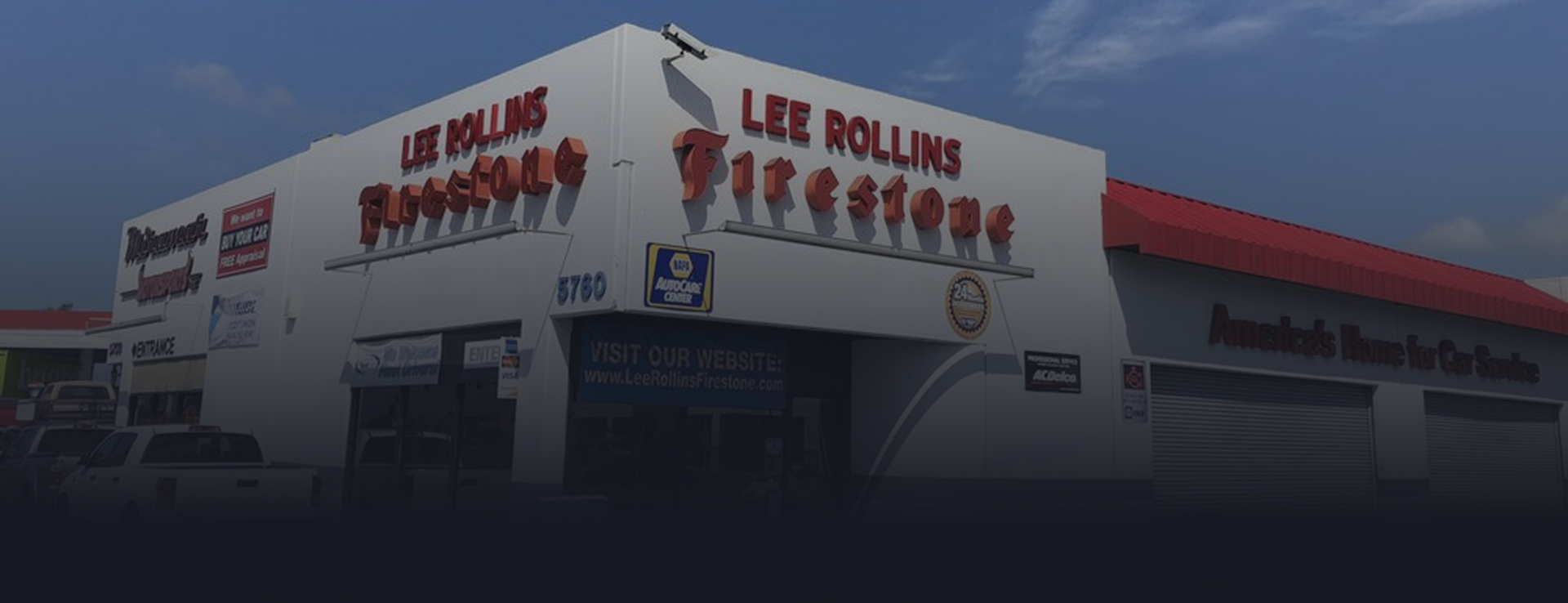 LEE ROLLINS Firestone shop with red signage on a white building under a blue sky | Lee Rollins Firestone