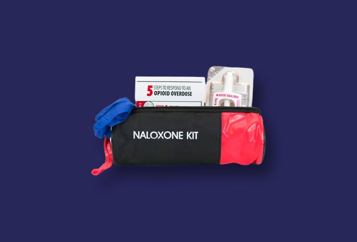 Naloxone kit: Black case with red end, contents include box of syringes, bottle, blue bandage.