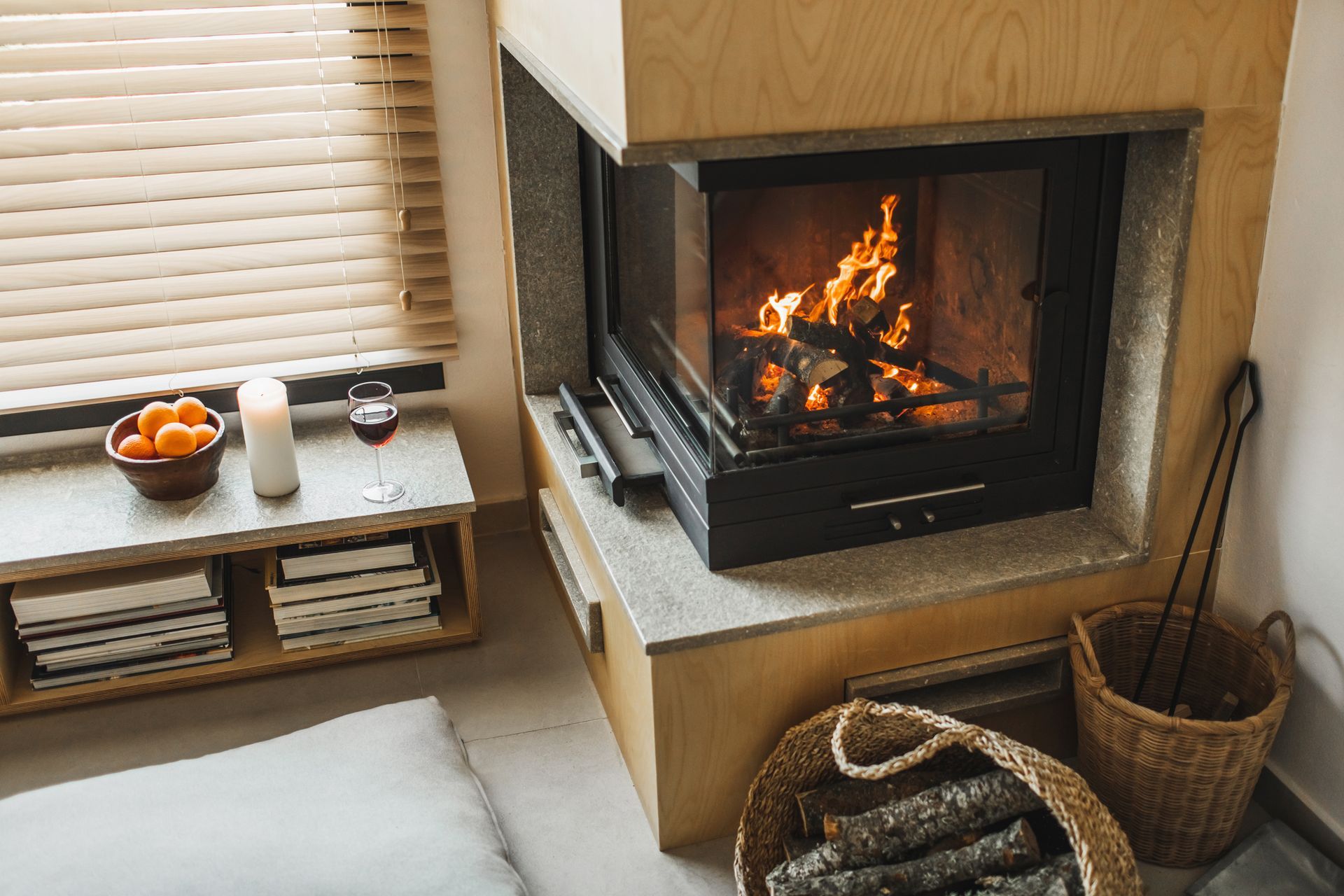 A living room with a fireplace and a basket of logs.