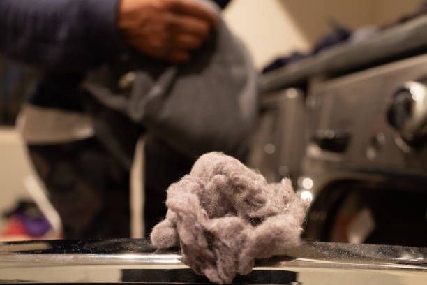 a person is cleaning a lint from a dryer with a vacuum cleaner .