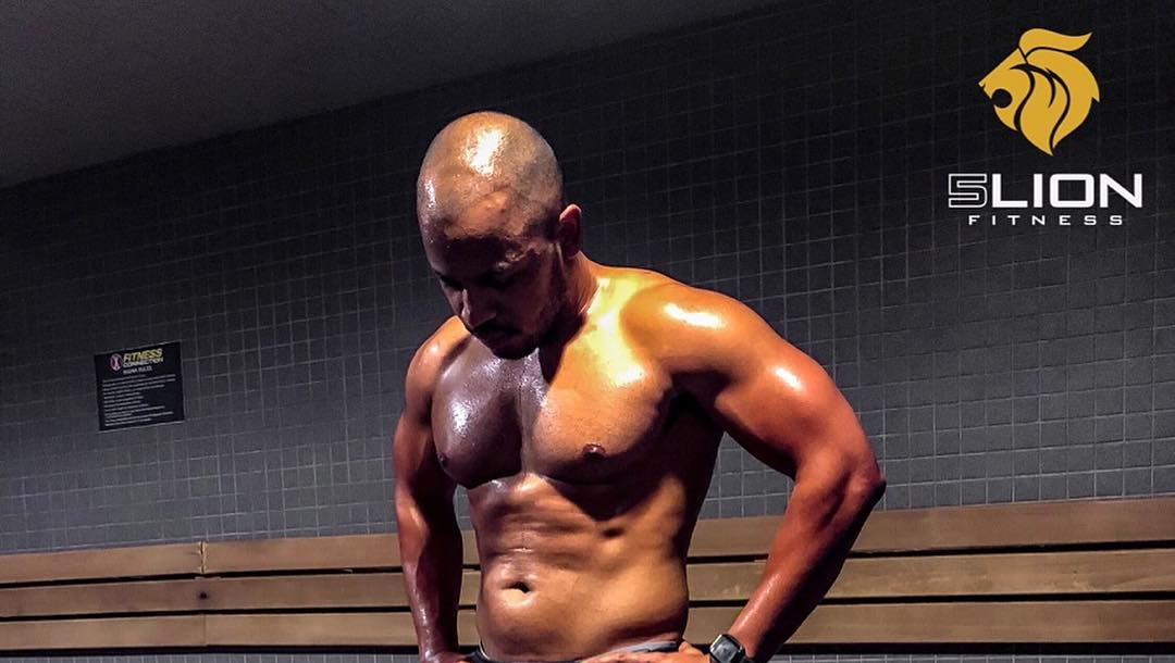 A man without a shirt is standing in front of a lion logo