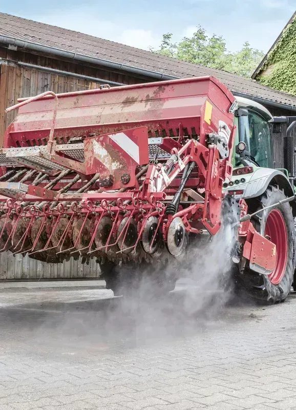 A red and white tractor is driving down a brick road.