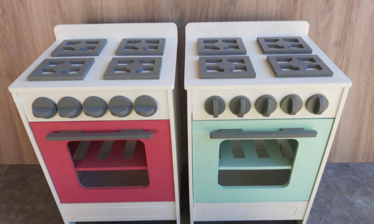 Dos estufas de juguete, una con detalles rojos y la otra verde. Ambas tienen perillas y tapas.