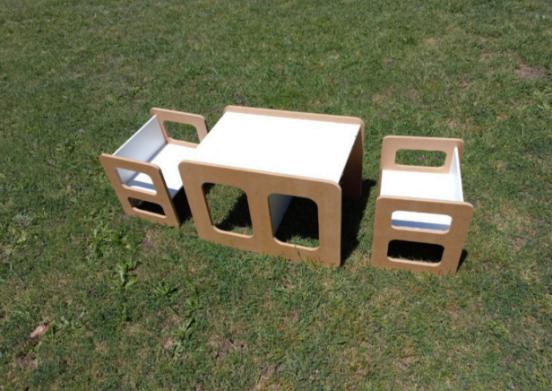 Pequeña mesa de madera y dos sillas sobre césped.