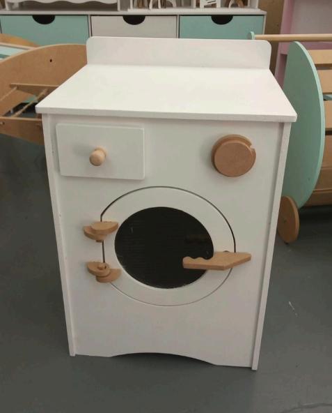 Lavadora de juguetes de madera blanca con puerta redonda, pomos de madera y cajón.