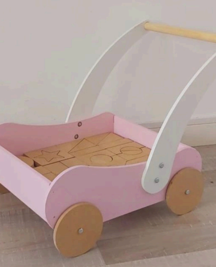 Andador de madera rosa y blanco con bloques de madera en su interior.