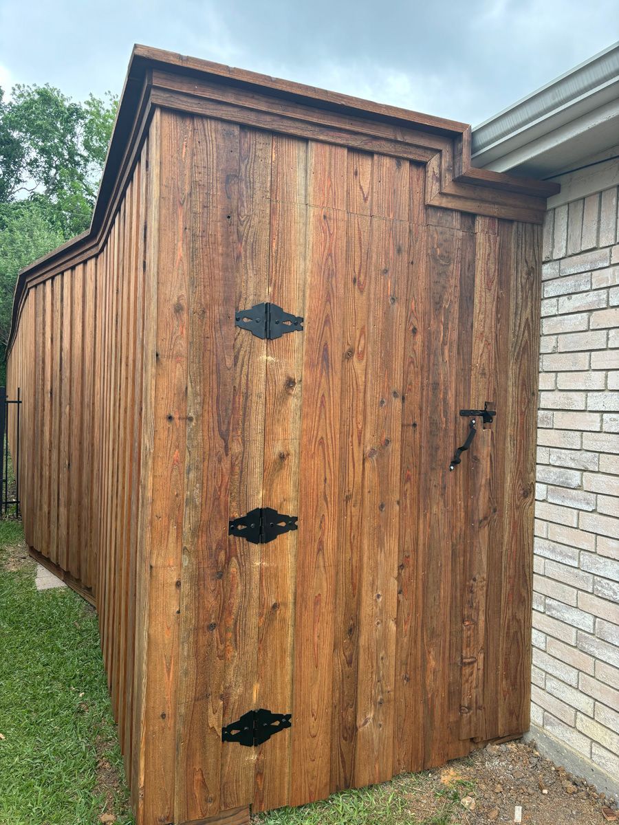 A wooden fence is sitting next to a brick building.