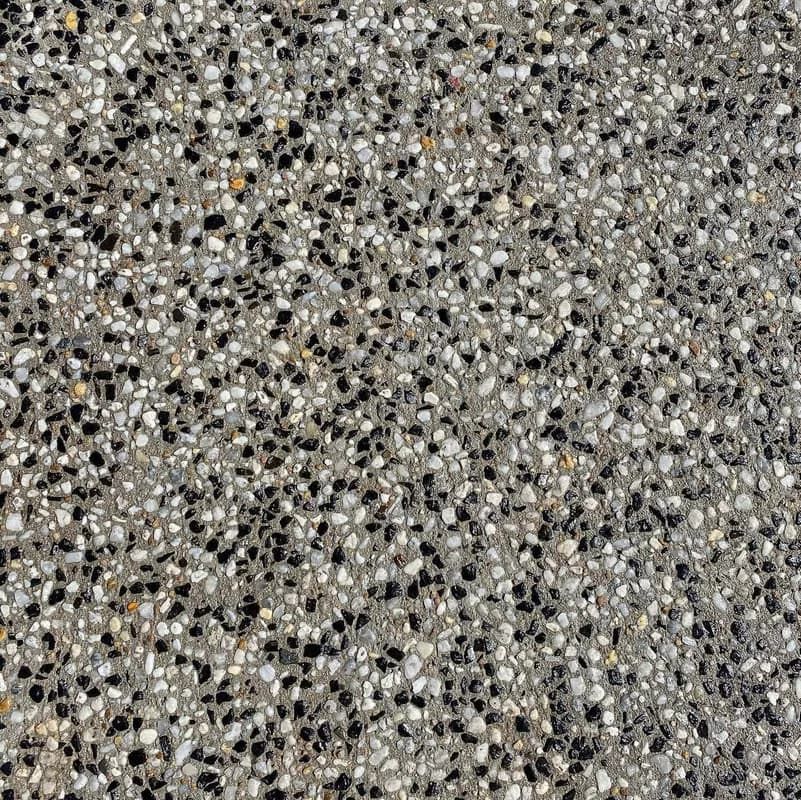 Close-up of a speckled concrete surface; shades of gray, black, white, and yellow aggregate.