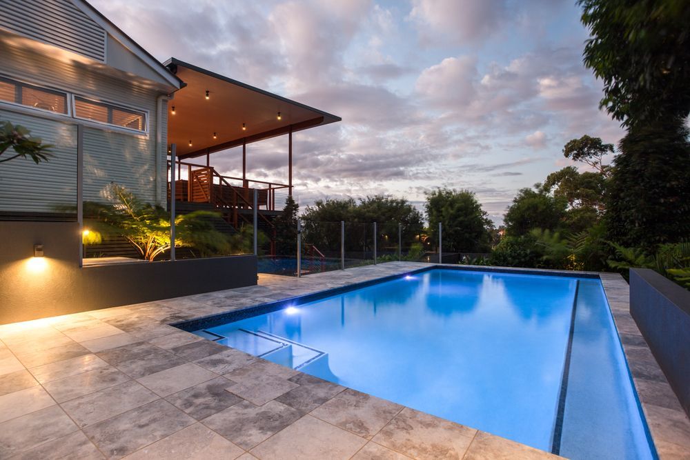 Elegant swimming pool illuminated at night beside a contemporary home — SJ Pools and Concreting in Dubbo, NSW