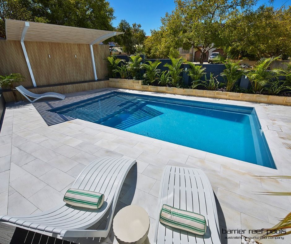 A Large Swimming Pool Surrounded by Trees and Lawn Chairs in a Backyard — SJ Pools and Concreting in Orange, NSW
