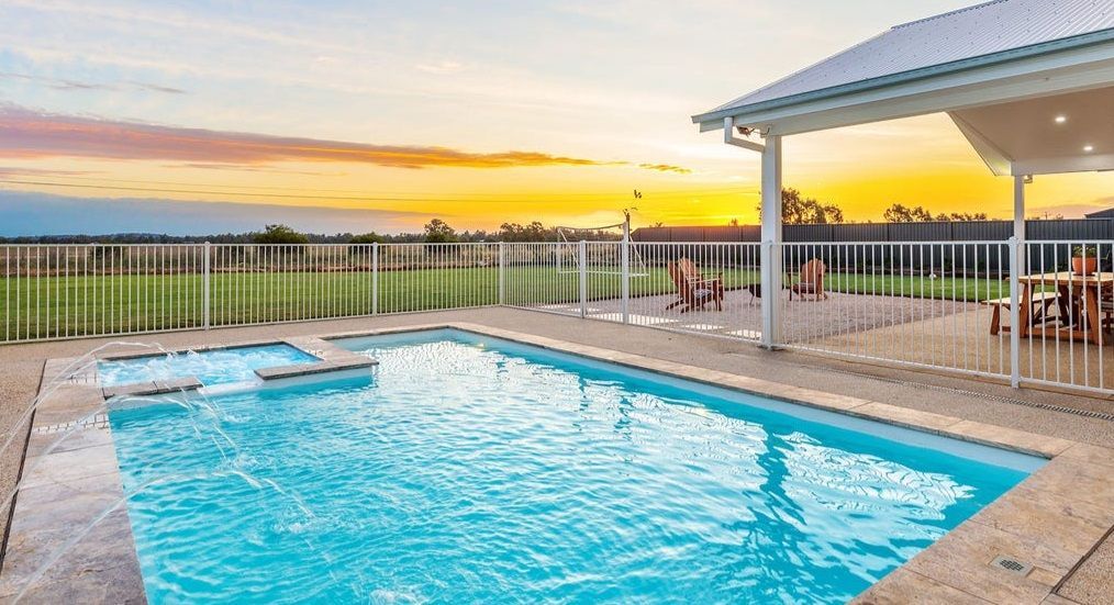 A swimming pool with spa next to it and sunset — SJ Pools and Concreting in Nyngan, NSW