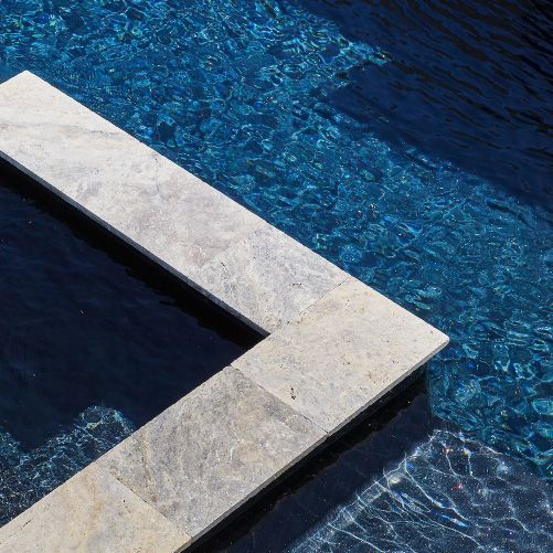 Blue water pool with light stone coping.