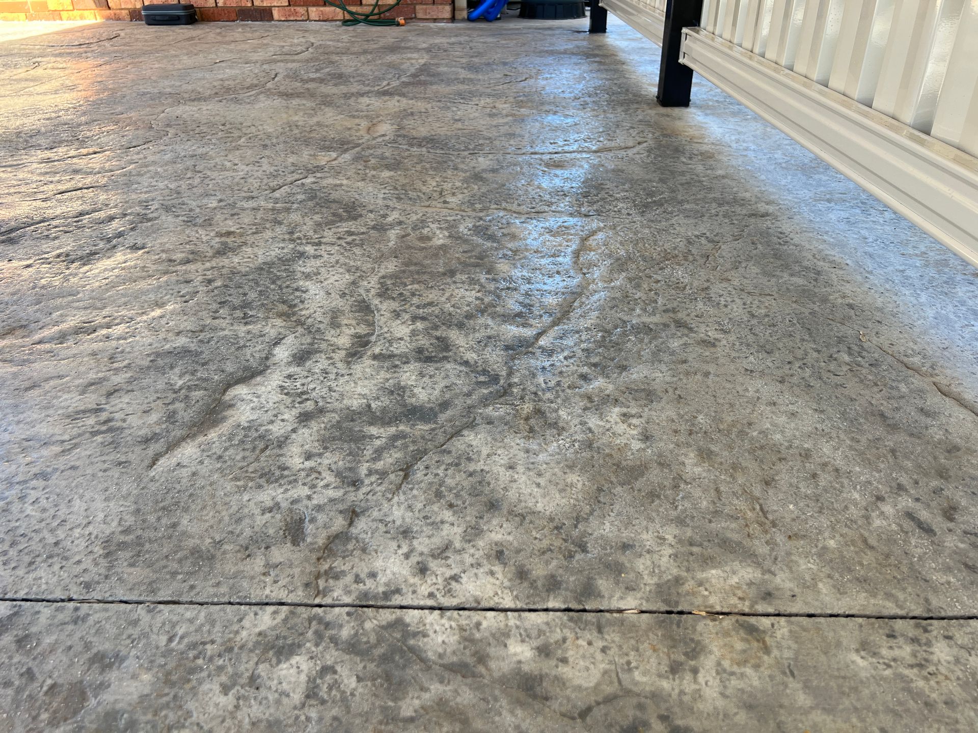 Gray, textured concrete surface with a decorative pattern, near a white building.