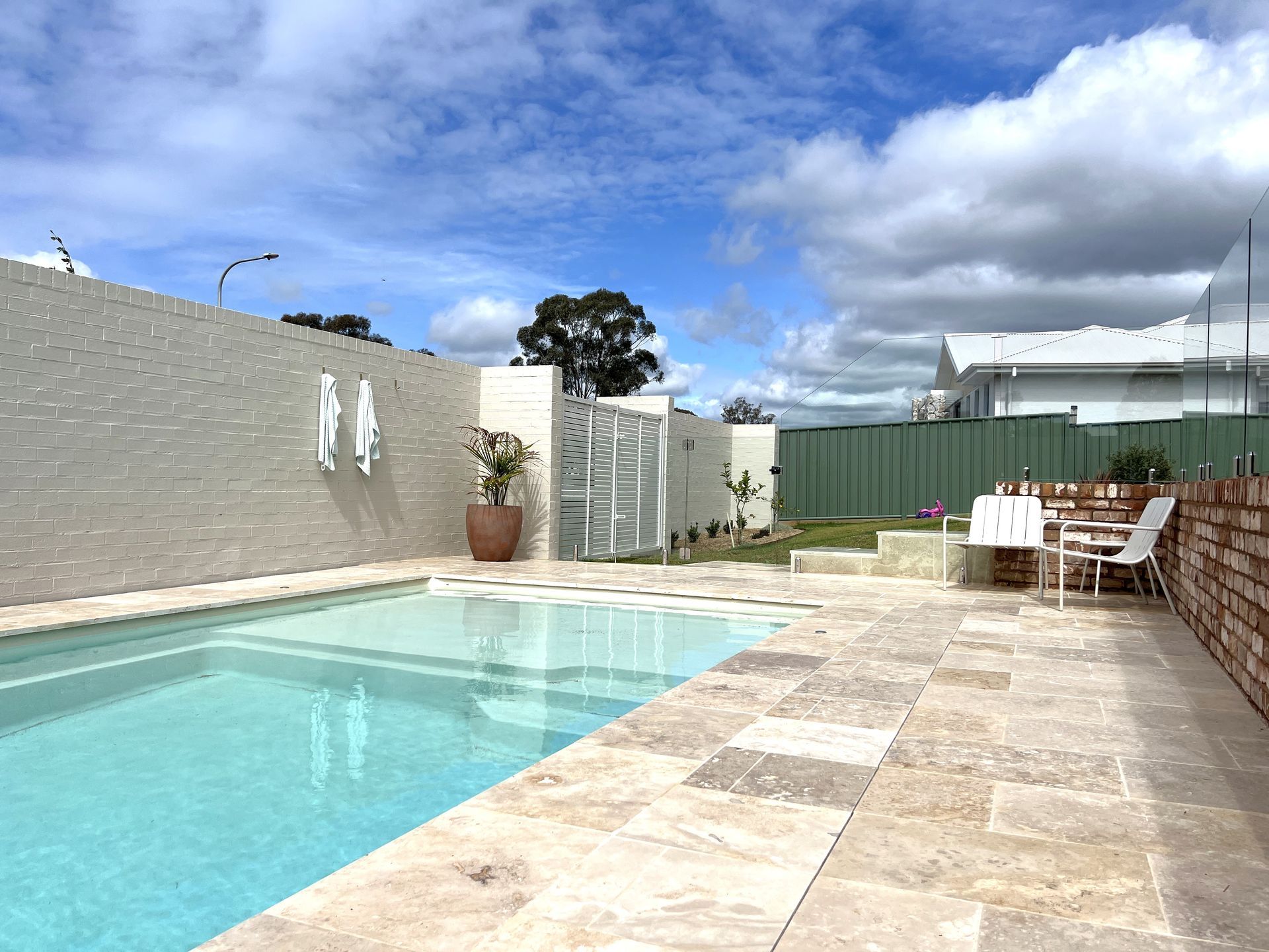 There is a Large Swimming Pool in Front of a Large Glass House — SJ Pools and Concreting in Dubbo, NSW