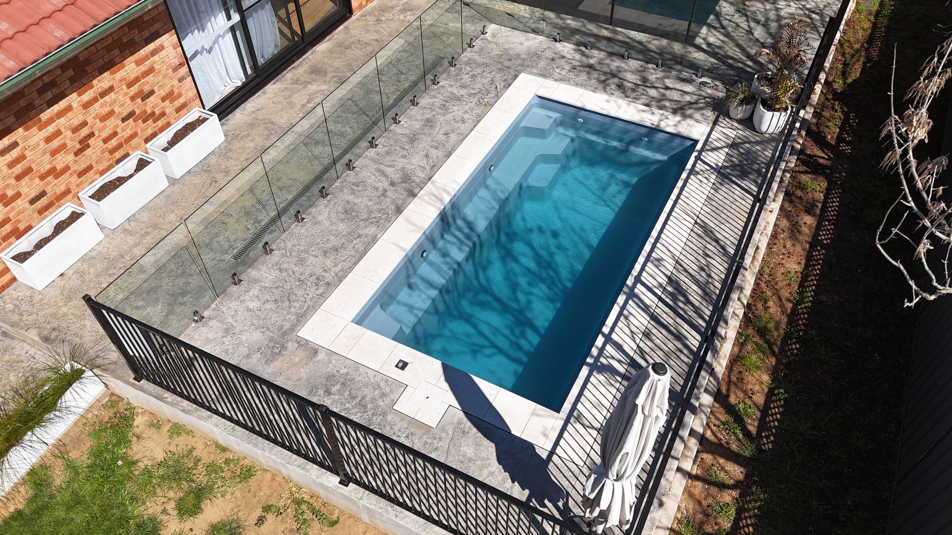 A birds eye point of view of a pool surrounded by a glass fence— SJ Pools and Concreting in Nyngan, NSW