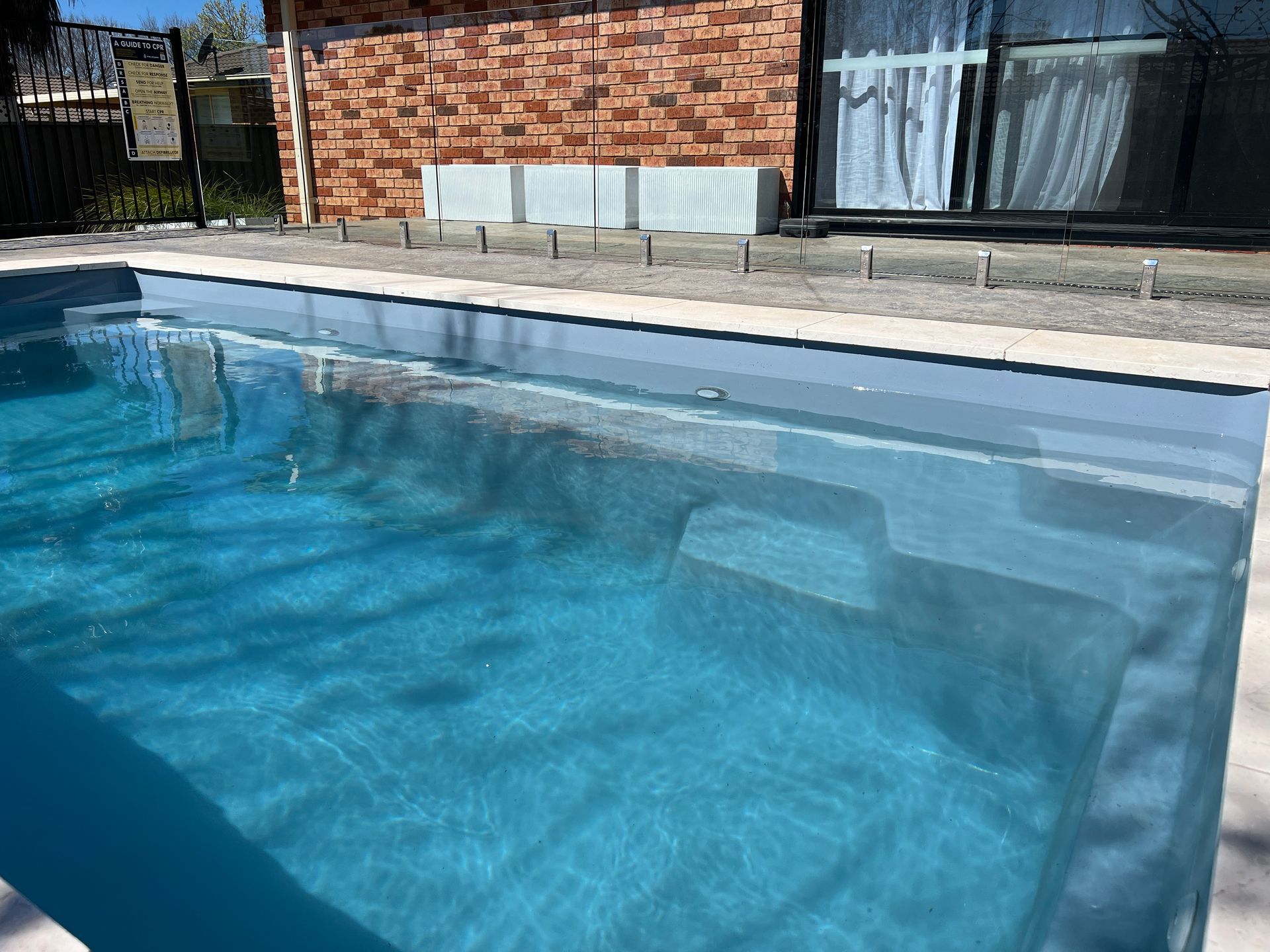 Swimming pool with blue water next to a brick building.