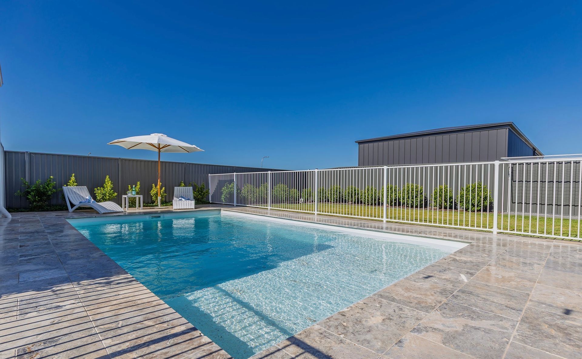 A Large House With a Swimming Pool in Front of It — SJ Pools and Concreting in Dubbo, NSW
