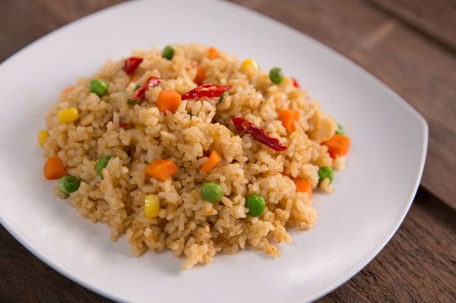 A colorful plate of fried rice, featuring fluffy grains of rice with assorted vegetables, eggs, and savory seasonings