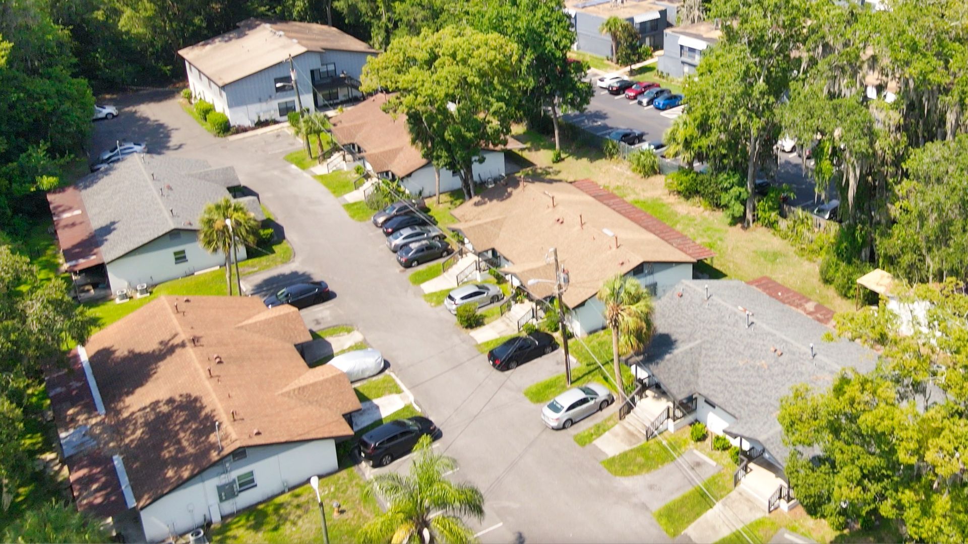 An aerial view of a residential neighborhood with lots of cars parked on the side of the road.