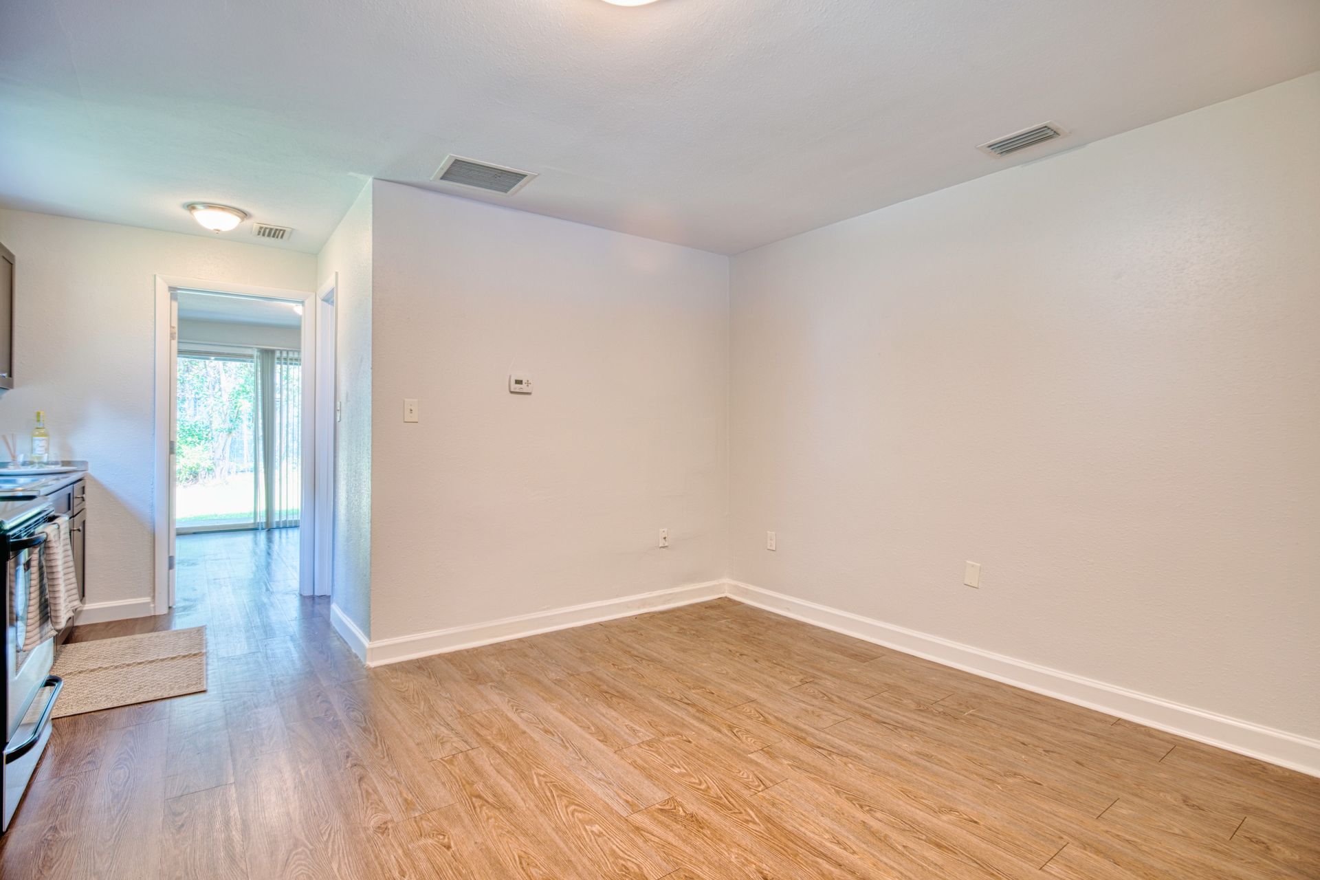 An empty living room with hardwood floors and white walls.
