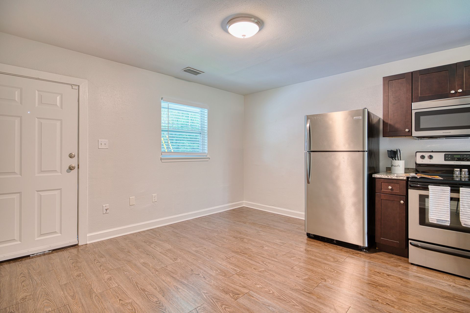 A kitchen with a stainless steel refrigerator , stove , and microwave.