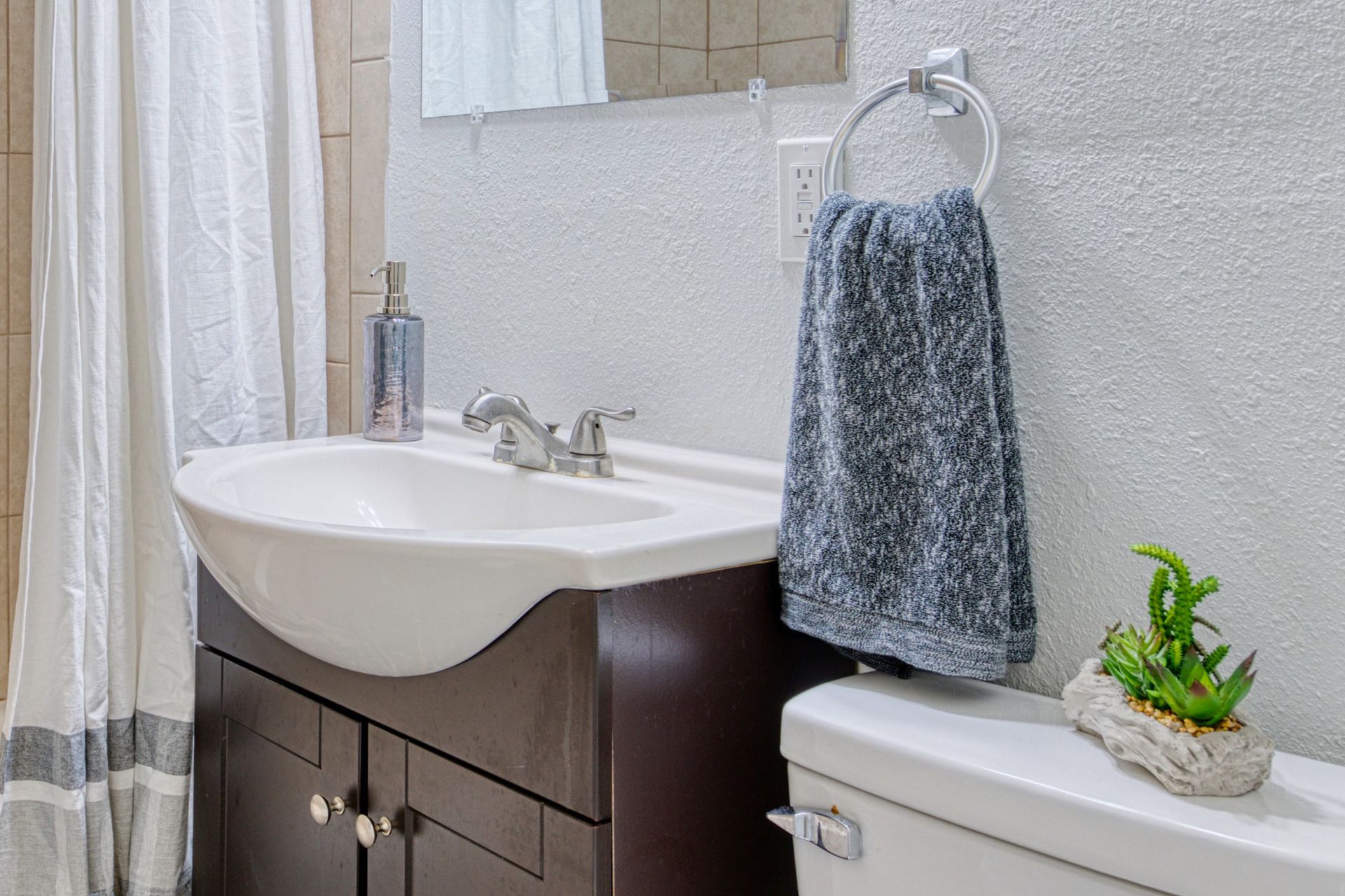 A bathroom with a sink , toilet , mirror and shower curtain.