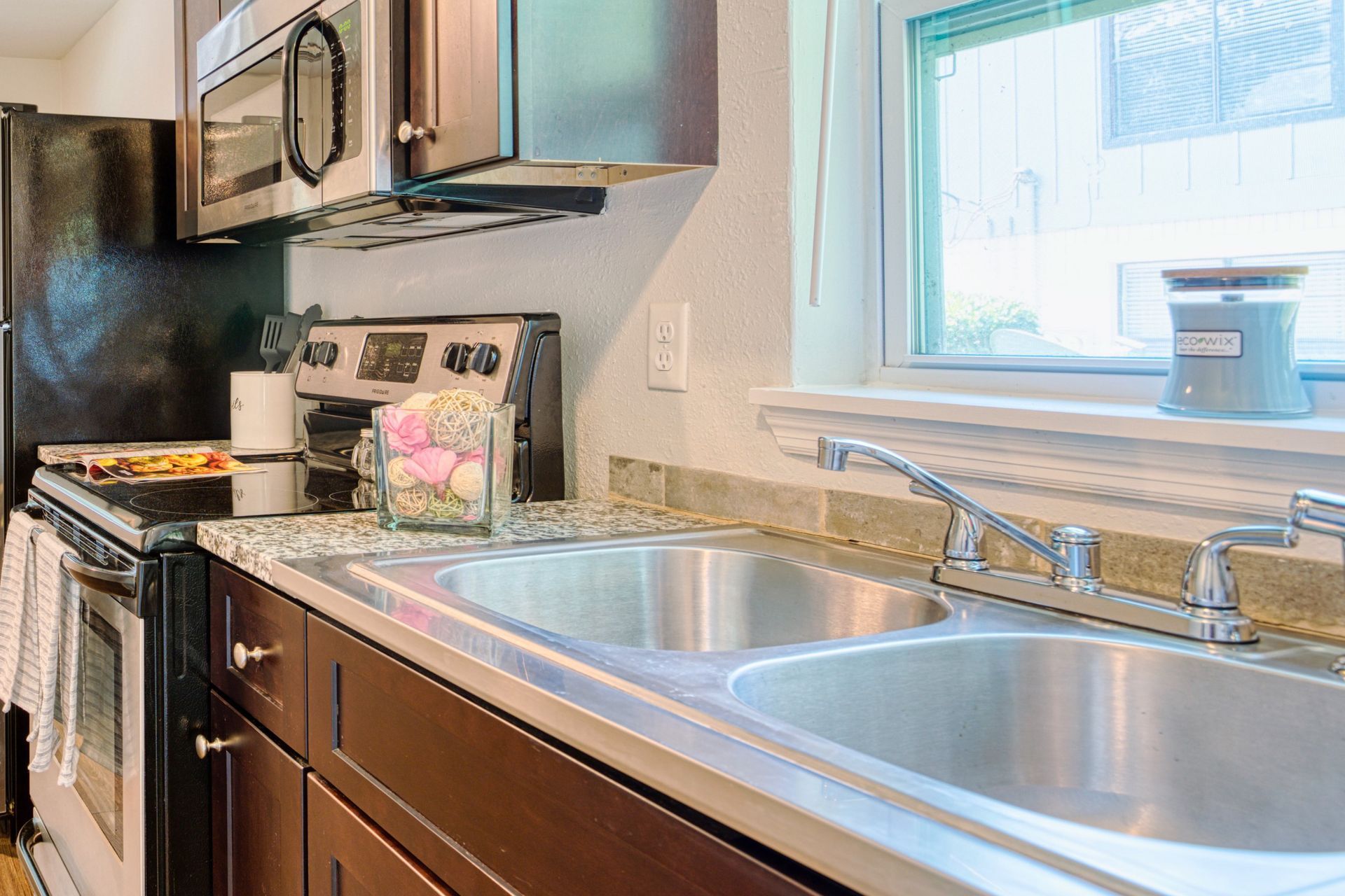A kitchen with a sink , stove , refrigerator and microwave.