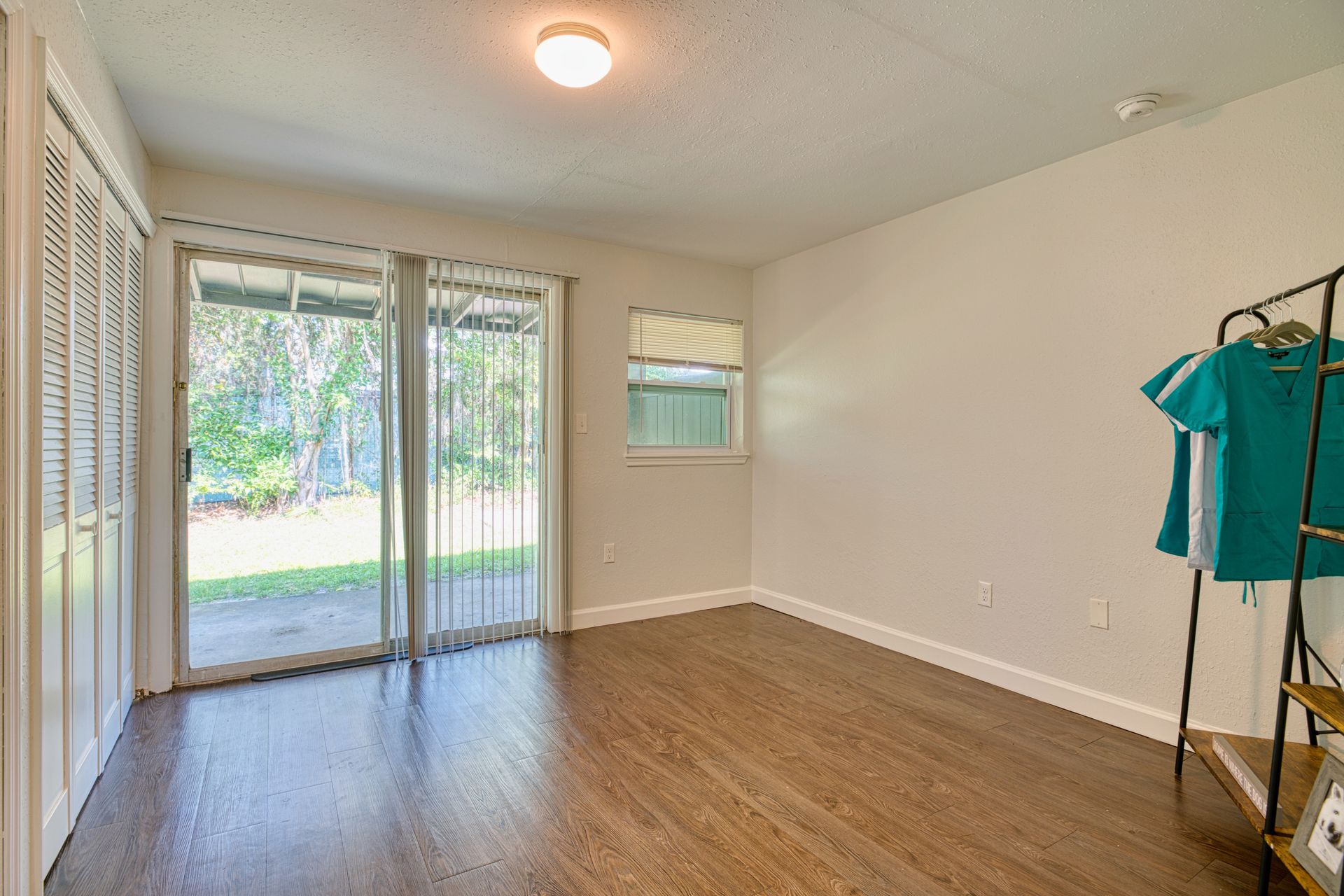 An empty living room with hardwood floors and sliding glass doors.