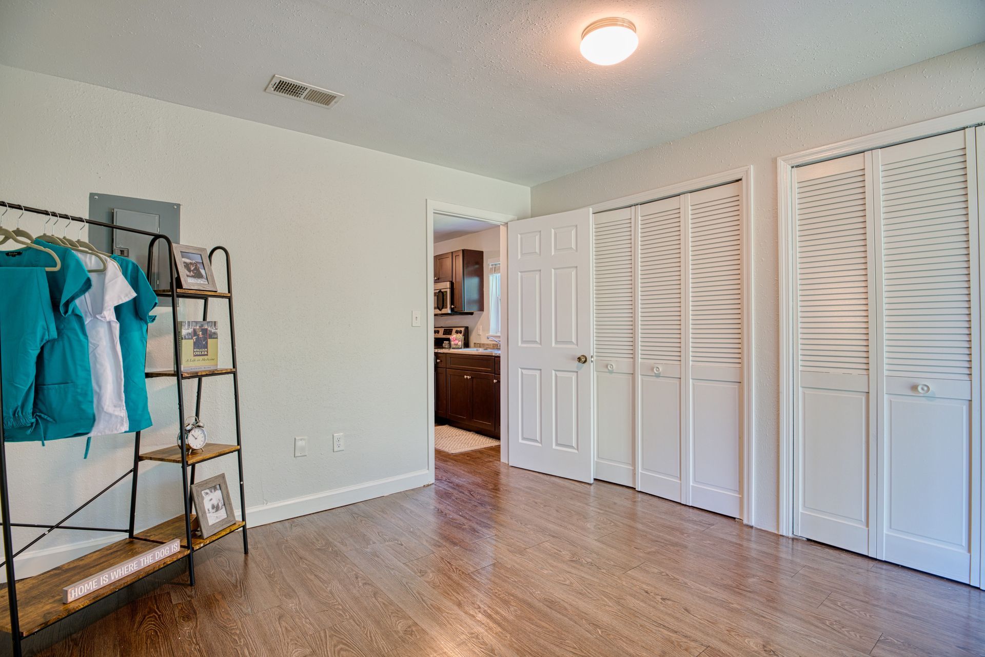 A bedroom with hardwood floors , white walls and closets.