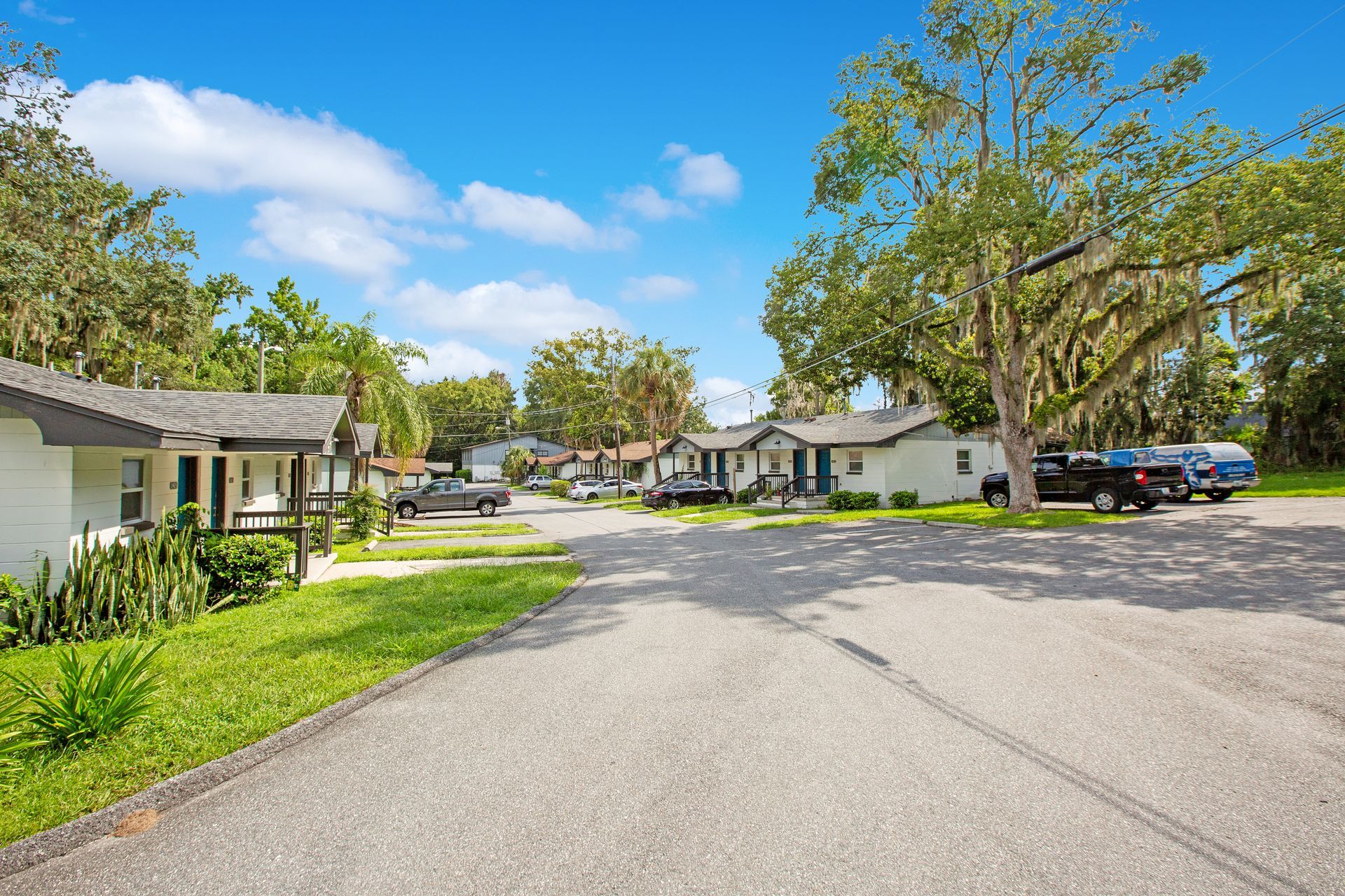 A row of apartment buildings on a residential street with cars parked on the side of the road.