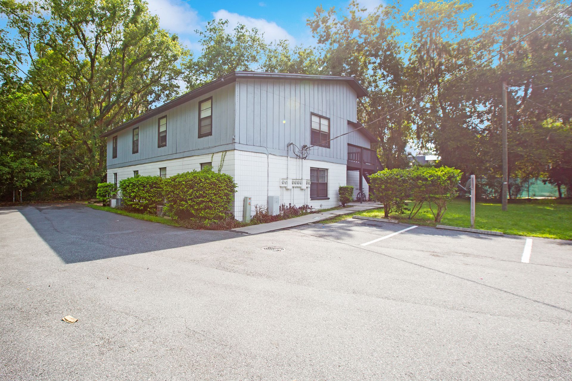 A building with a lot of windows is surrounded by trees and a parking lot.