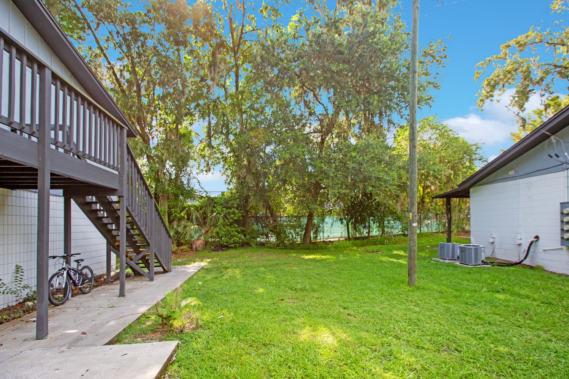 A lush green yard between two buildings with stairs leading up to the second floor.