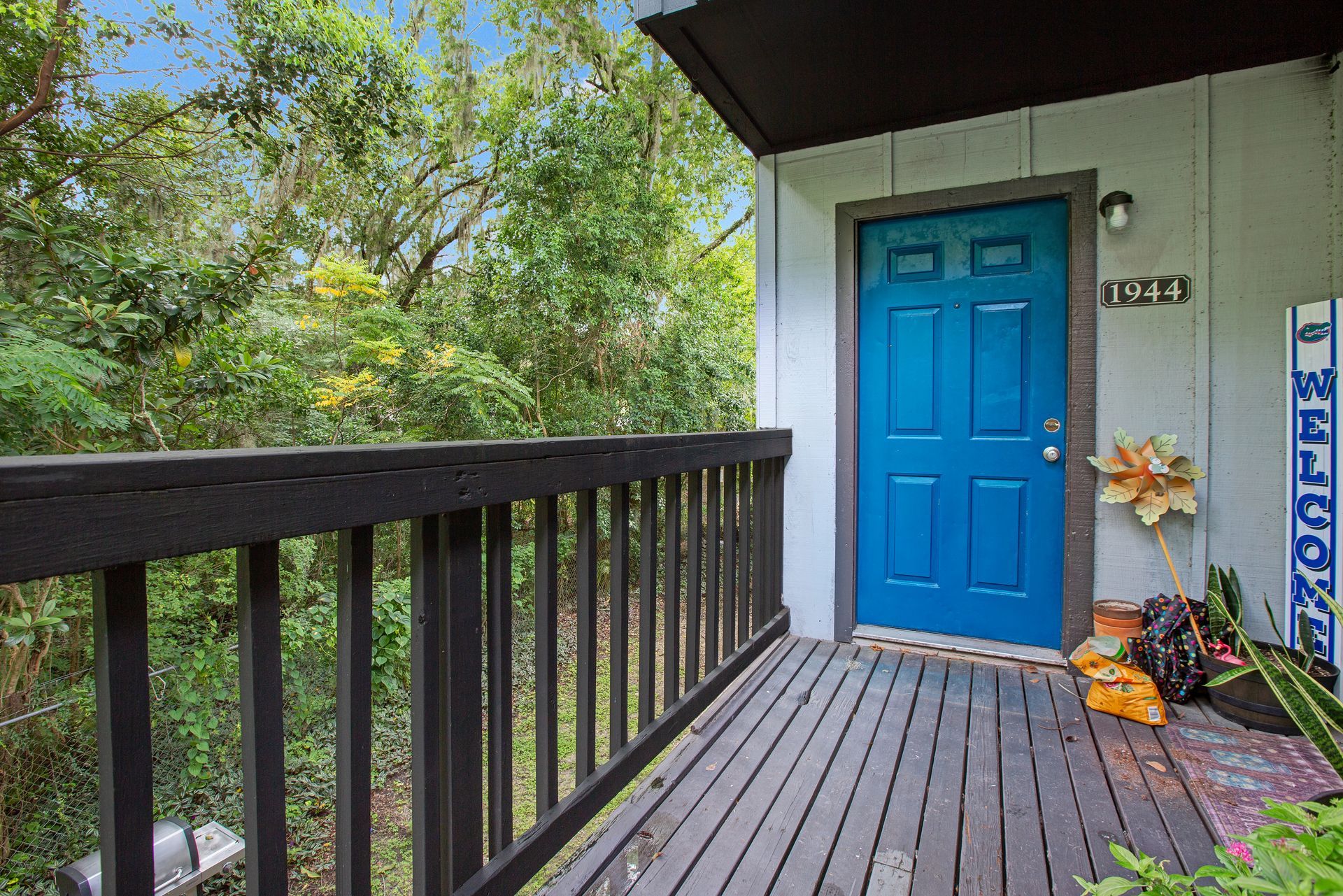 The front door of an apartment with a blue door and a wooden deck.